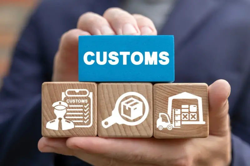 Klocki z symbolami celnymi i napisem "CUSTOMS" ilustrują proces odprawy towarów importowanych.
